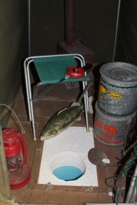 Ice fishing display of pretend ice fishing hole, seat, and fish.